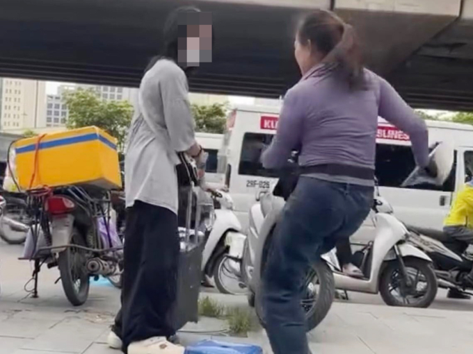 1-1751846248-8411-1751846399 Hình ảnh người phụ nữ bán trà đá (bên phải) đuổi cô gái đứng trên vỉa hè. Ảnh: Cắt từ video