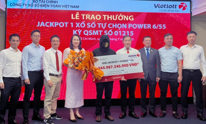 vietlott-1753175320-9571-1753175497 Ông N.P. (đeo mặt nạ) nhận thưởng từ đại diện Vietlott chiều 22/7. Ảnh: Minh Anh